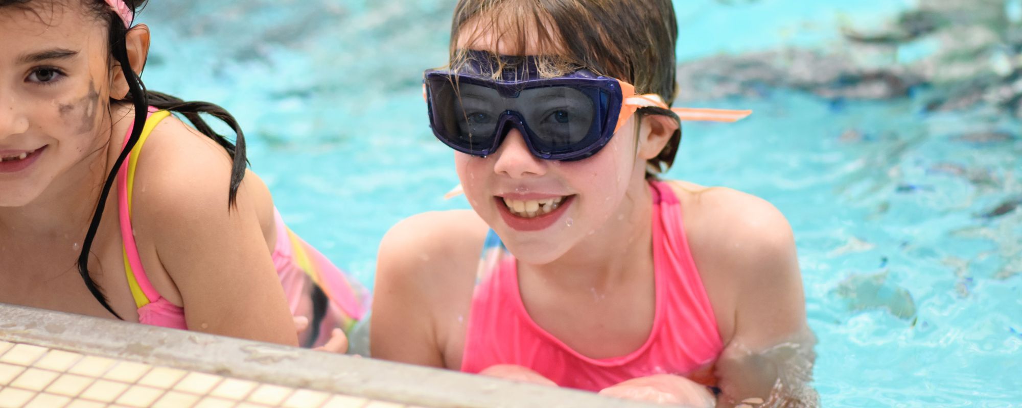 Two kids swimming and smiling in the AFC pool