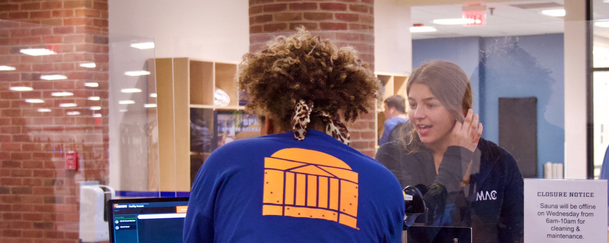 Student Staff helping out a patron at a facility front desk